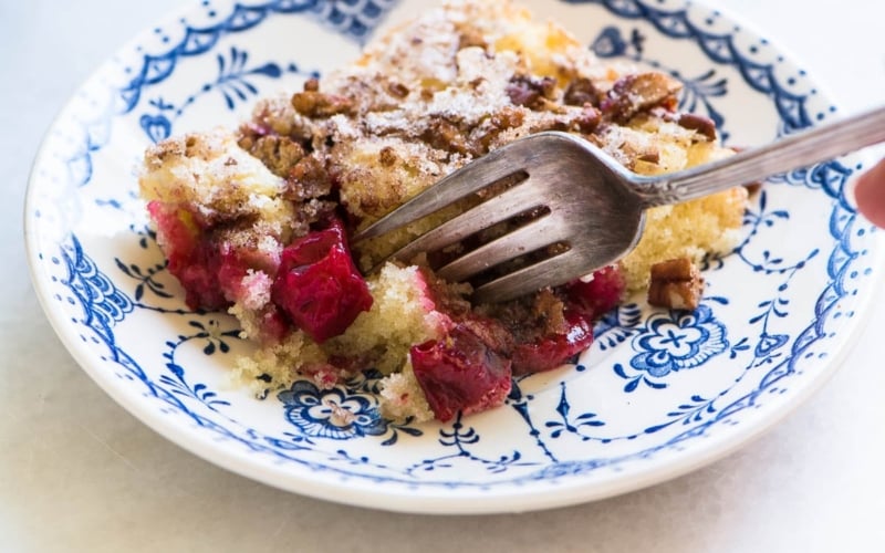 A piece of plum blitz kuchen cake on a blue and white plate with fork