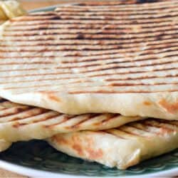 Laffa bread with grill marks, piled on a plate.