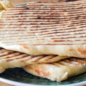 Laffa bread with grill marks, piled on a plate.