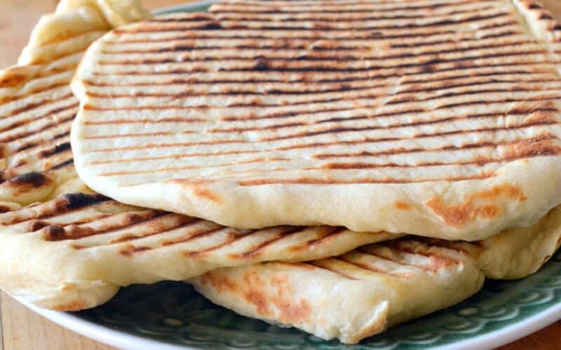 Laffa bread with grill marks, piled on a plate.