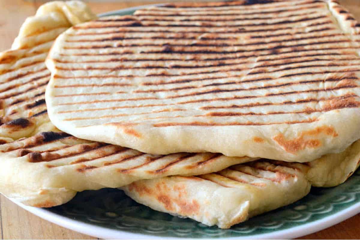 Laffa bread with grill marks, piled on a plate.