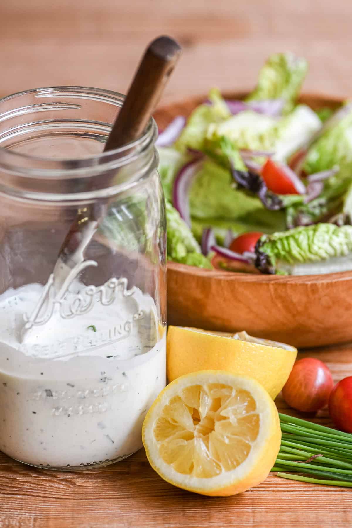 A salad with a jar of buttermilk dressing for a chicken salad.