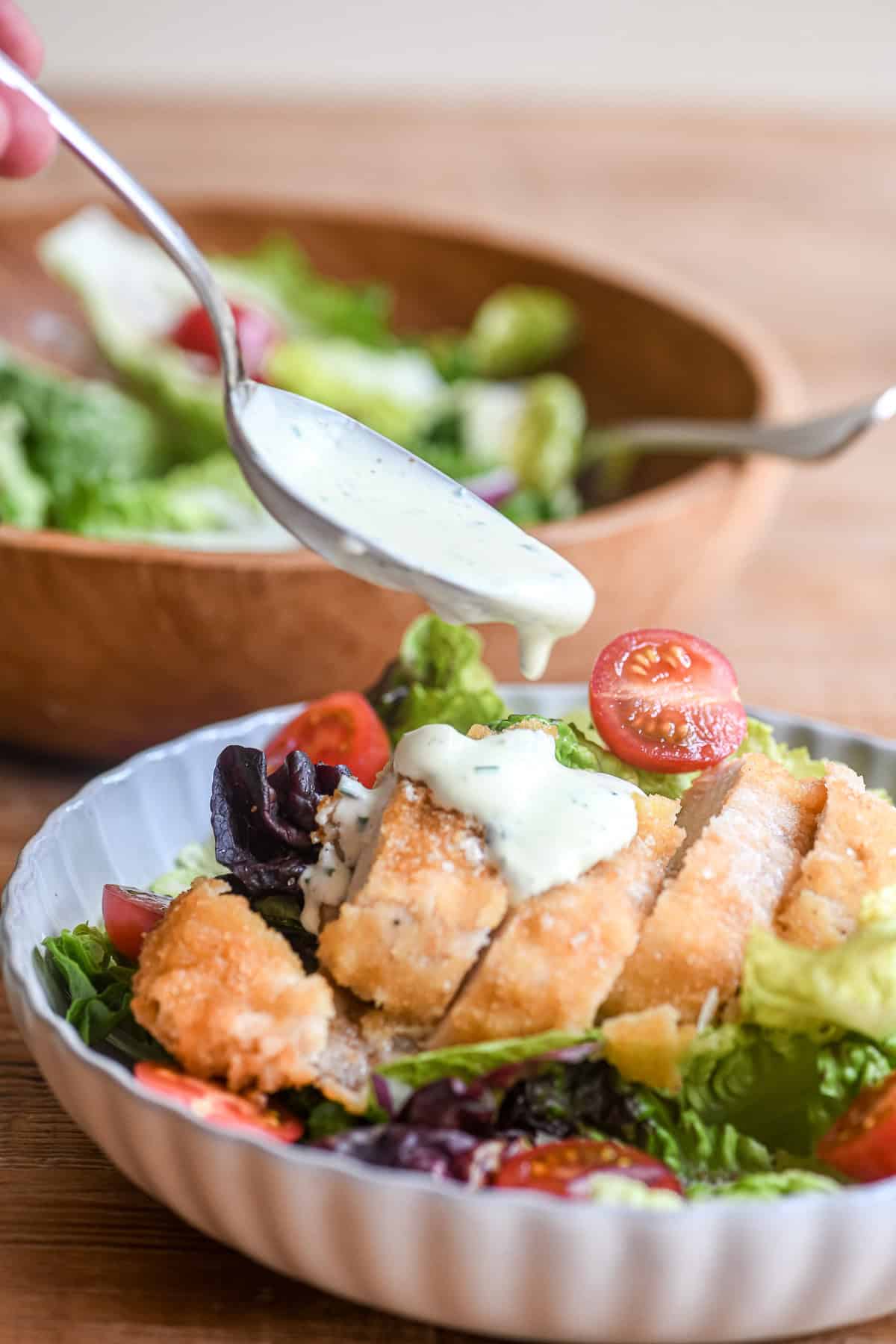 Spooning buttermilk dressing on a chicken salad.