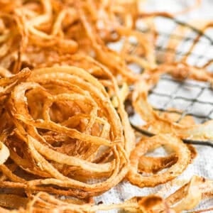 Crispy onion strings draining on a paper towel.