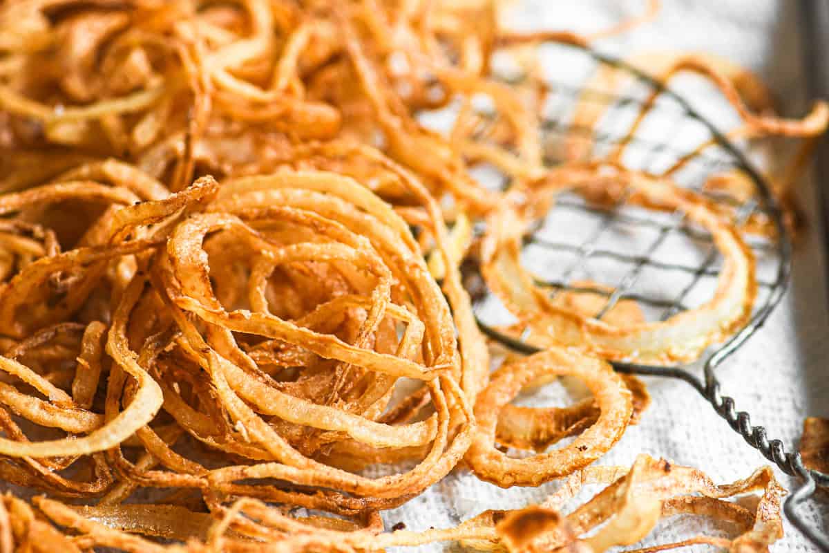 Crispy onion strings draining on a paper towel.