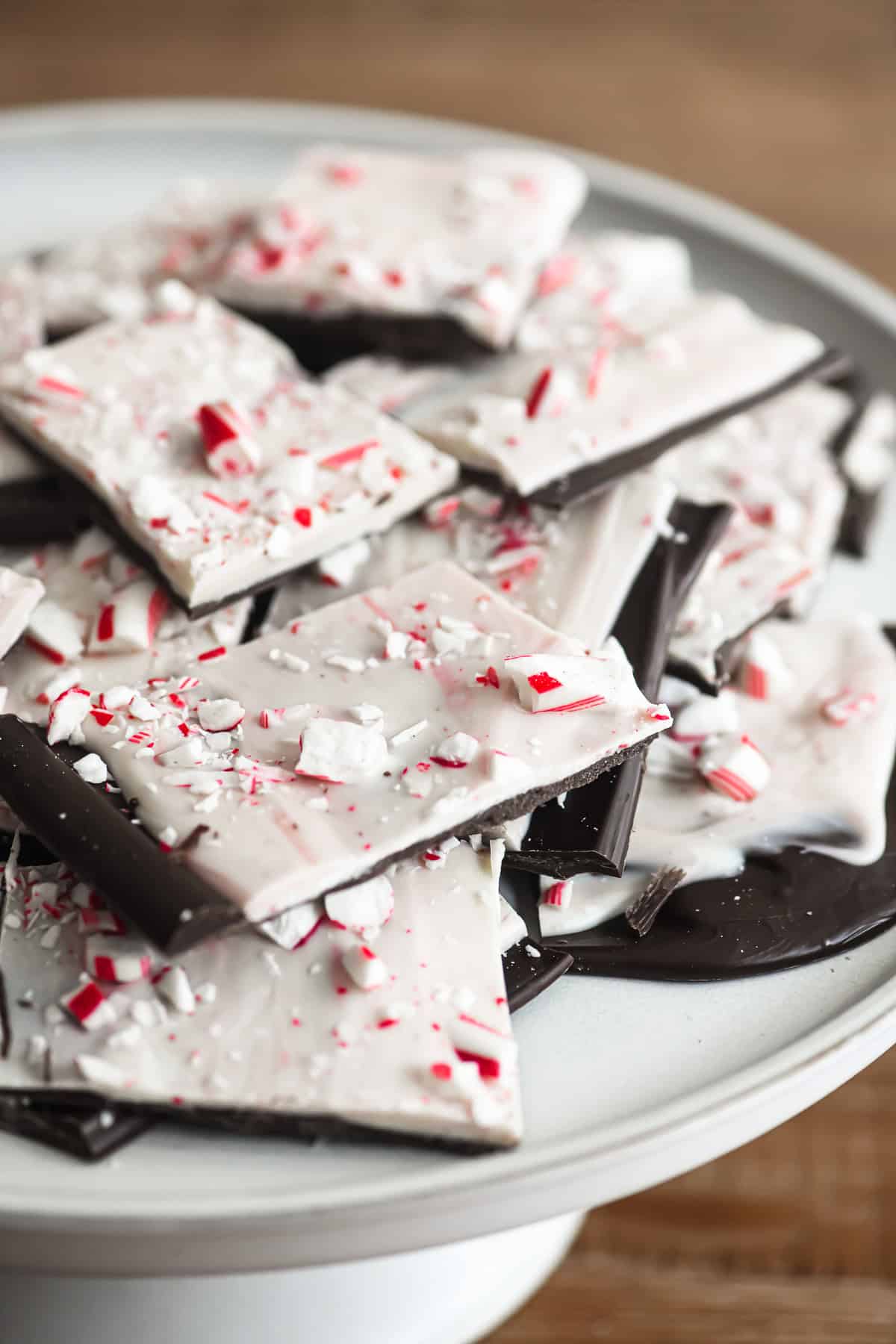 Peppermint Bark ~ an easy homemade chocolate candy made with both dark and white chocolate, and plenty of crushed candy canes! #recipe #easy #homemade #best #christmas #chocolate pieces of homemade peppermint bark on a cake stand.