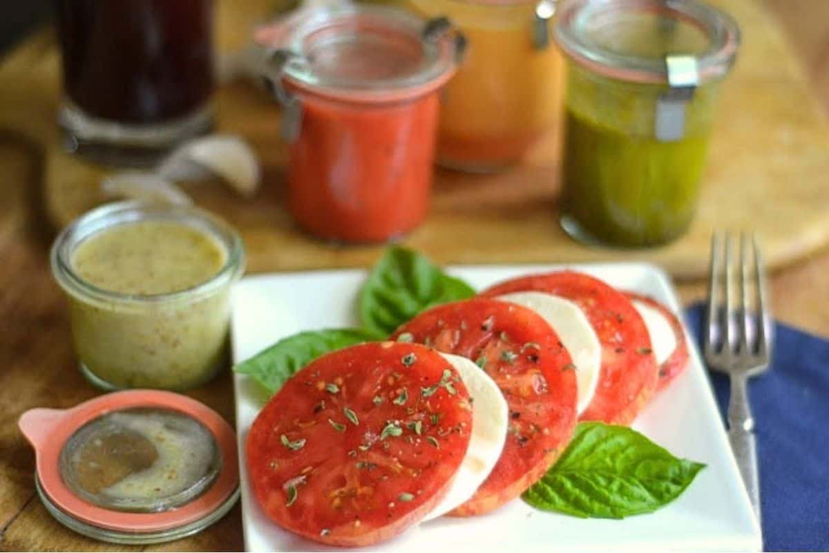 Homemade fruit based salad dressings around a tomato and mozzarella salad.