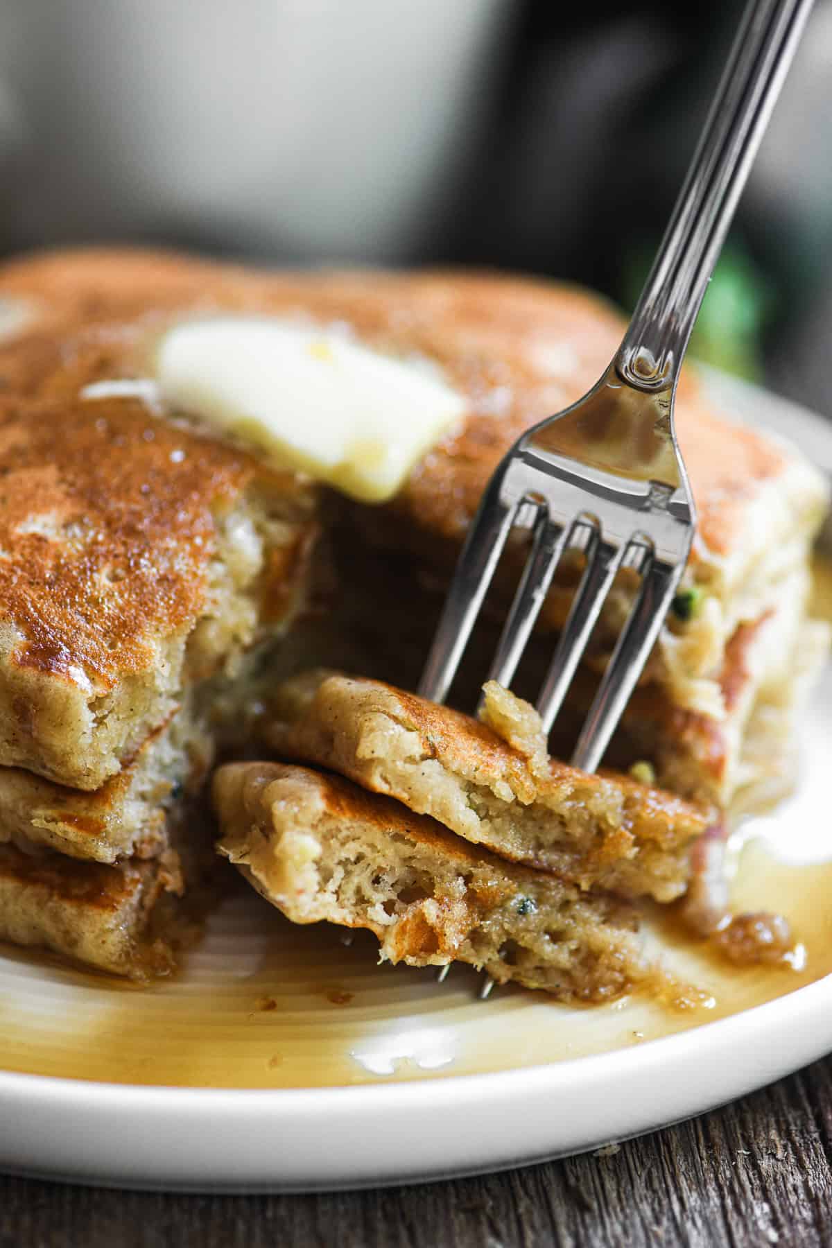 Taking a bite of a stack of zucchini bread pancakes.