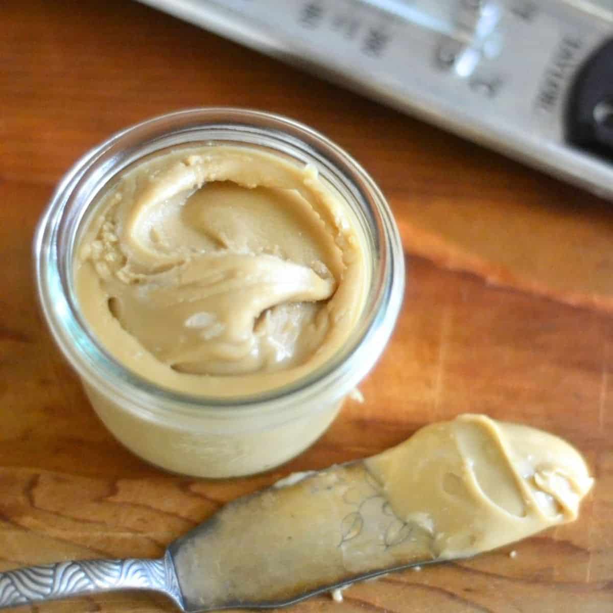 A small pot of maple cream with a spreading knife.