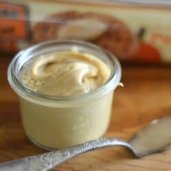 A small jar of maple cream with a package of English muffins.