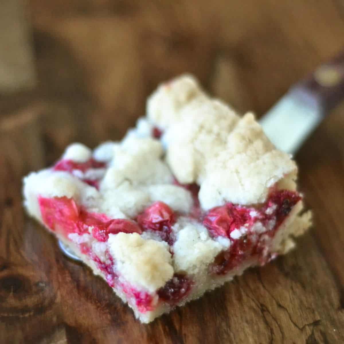 Serving a fresh cranberry bar, on a wooden table.