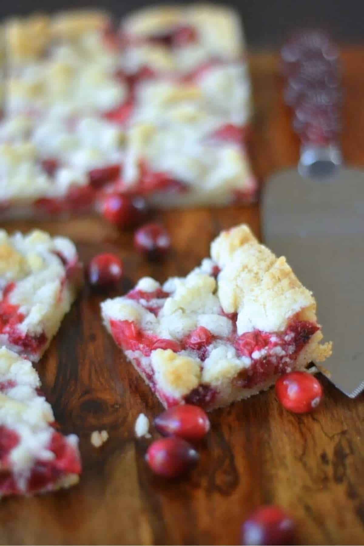 Slicing fresh cranberry bars, with fresh berries.