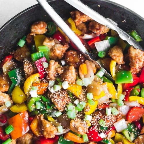 Colorful Firecracker Chicken in a wok with tongs