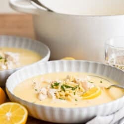 Greek avgolemono soup in bowls with fresh lemons.