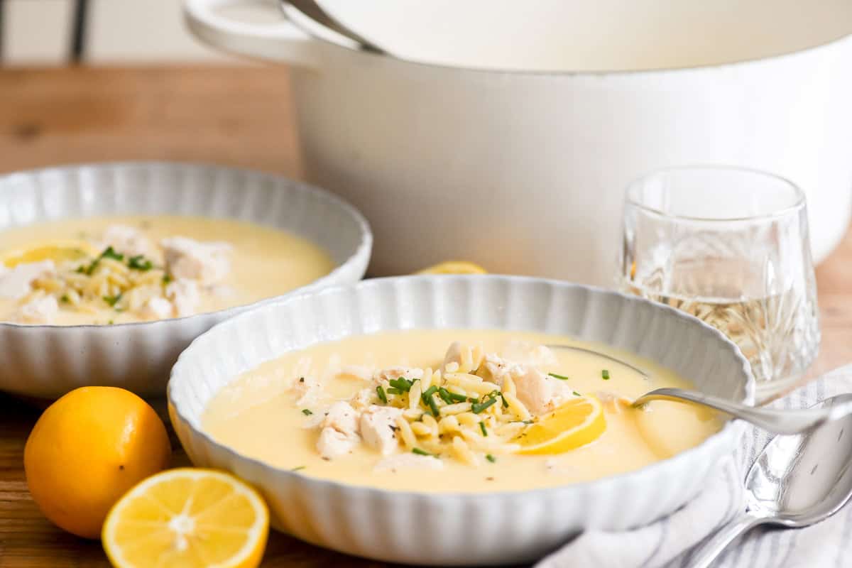 Greek avgolemono soup in bowls with fresh lemons.