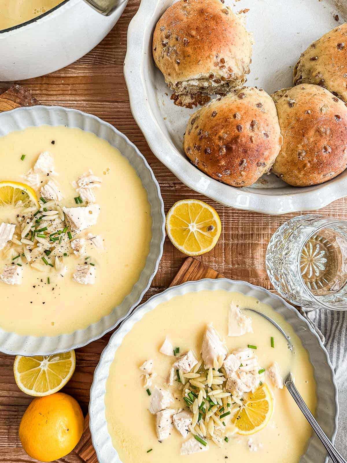 avgolemono soup in bowls with fresh lemons.