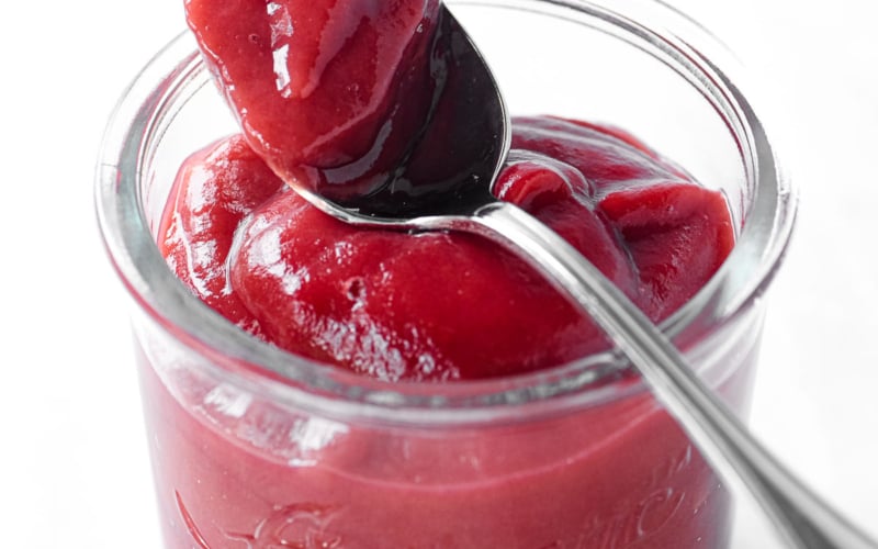 Bright red rhubarb butter, on a spoon.