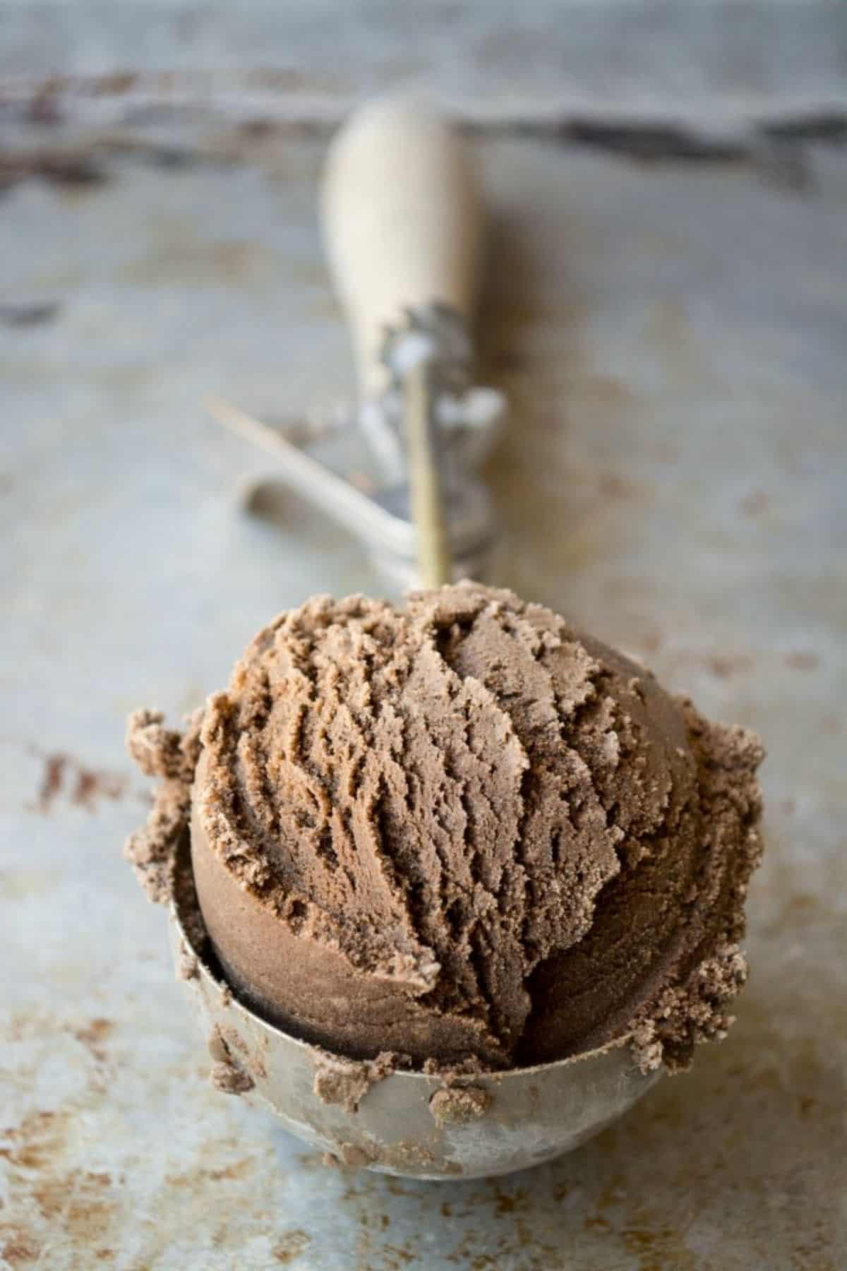 A scoop of black coffee ice cream in a vintage ice cream scoop.