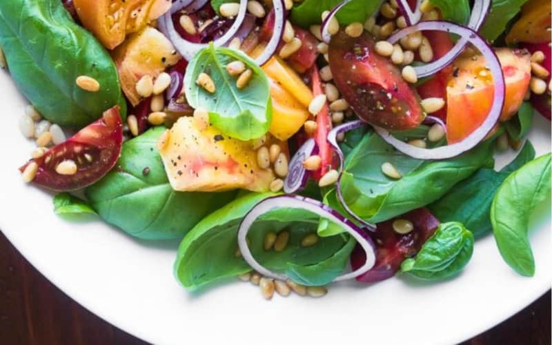 basil salad with colorful tomatoes and onions in a bowl.