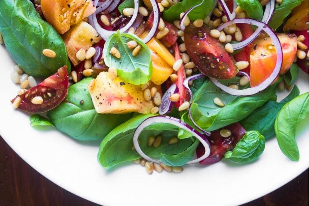 basil salad with colorful tomatoes and onions in a bowl.