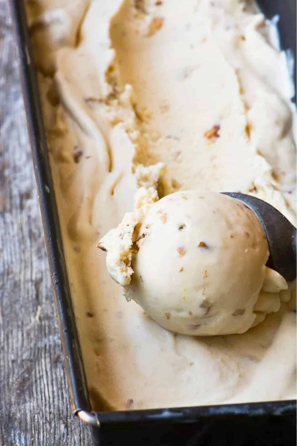 Scooping homemade maple walnut ice cream from a pan.