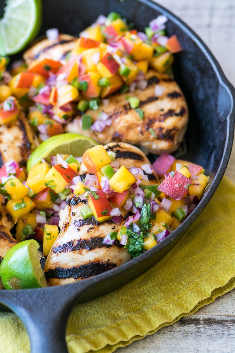 Pollo a la parrilla con salsa de melocotón y jalapeño en una sartén con limas frescas