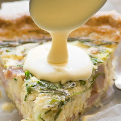 spooning hollandaise sauce on quiche