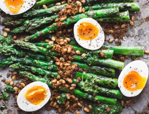 roasted asparagus on a baking sheet with soft boiled eggs