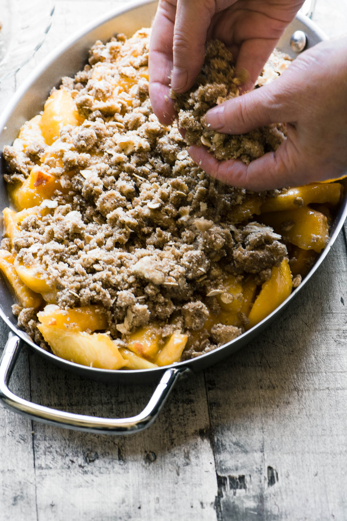 Crumbling topping over a gluten free spiced peach crisp