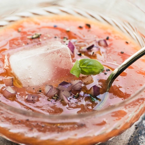 apricot gazpacho in a glass bowl with an ice cube