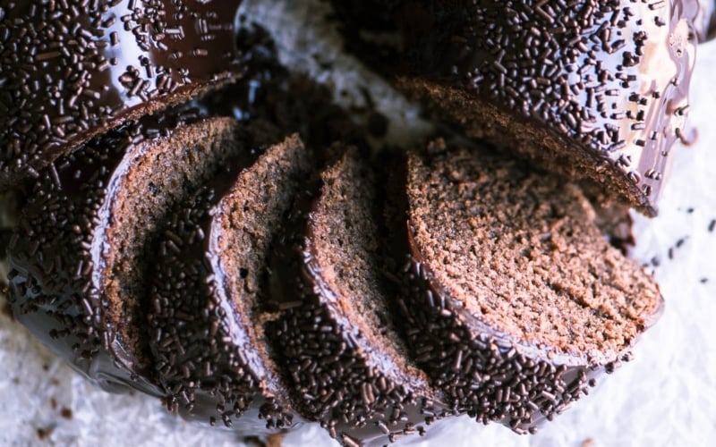 Chocolate Sour Cream Doughnut Bundt Cake, sliced, with sprinkles on parchment paper