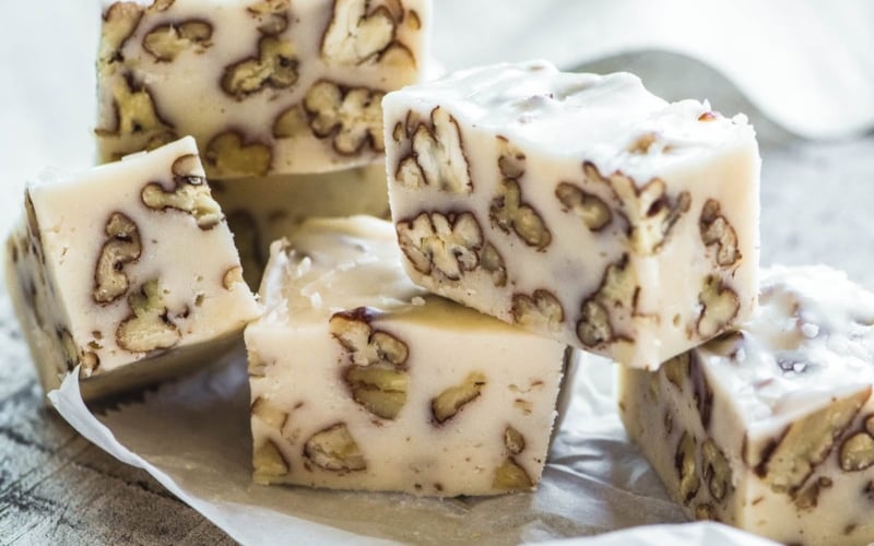 Pieces of Buttermilk Pecan Fudge stacked on parchment paper