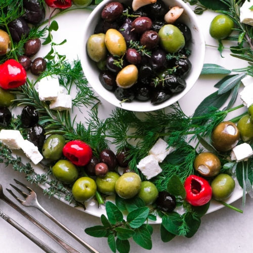Olive and Herb Appetizer Wreath on a white platter with cocktail forks