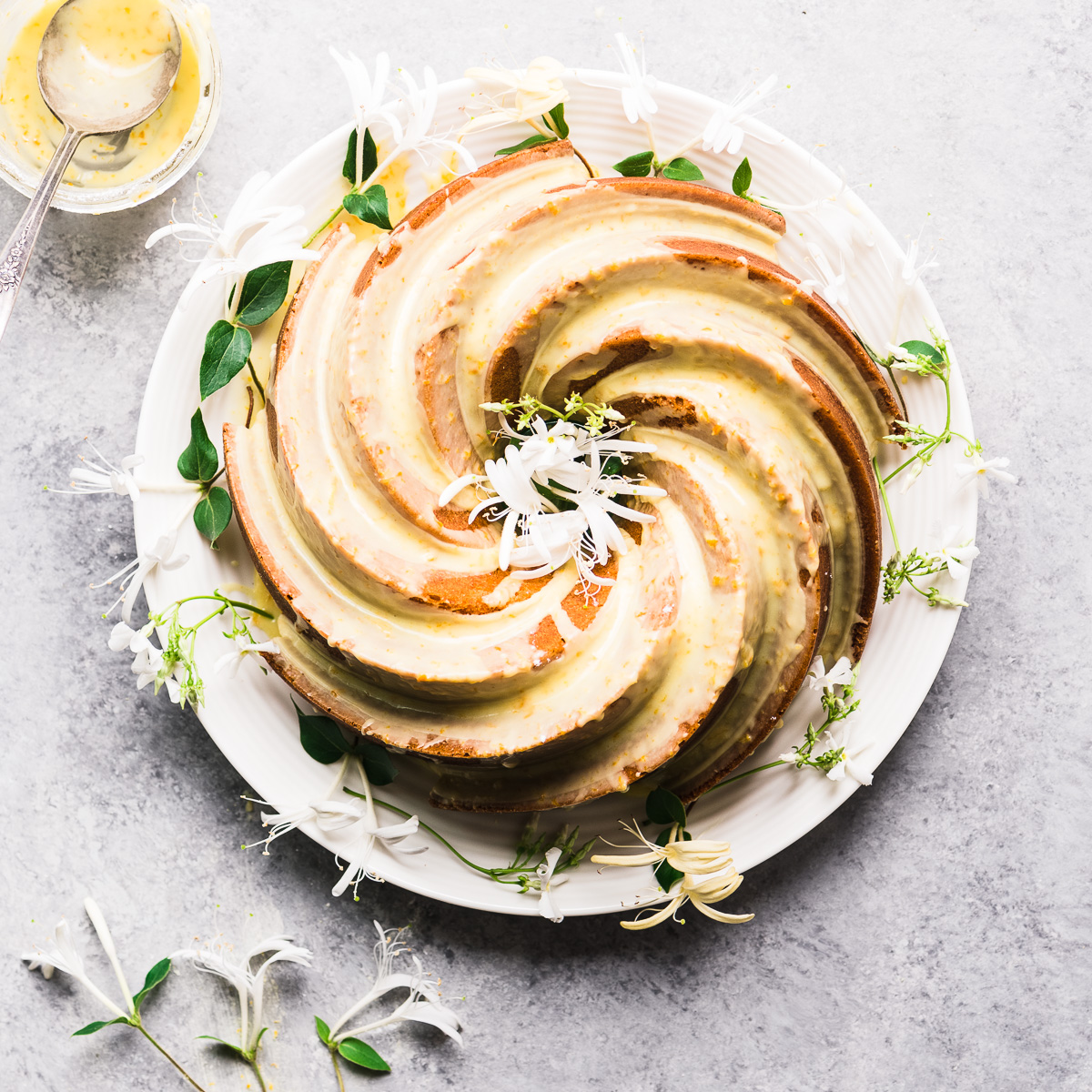 Orange Blossom Bundt Cake on a white plate with white flowers