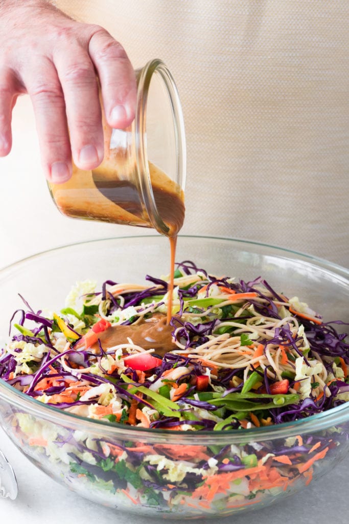 Pouring dressing on an Asian Slaw salad
