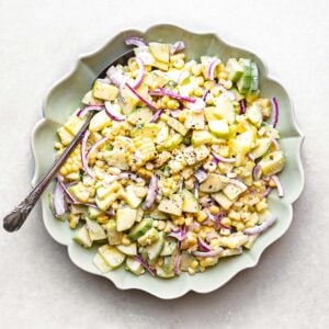 corn and cucumber salad in a bowl with serving spoon.