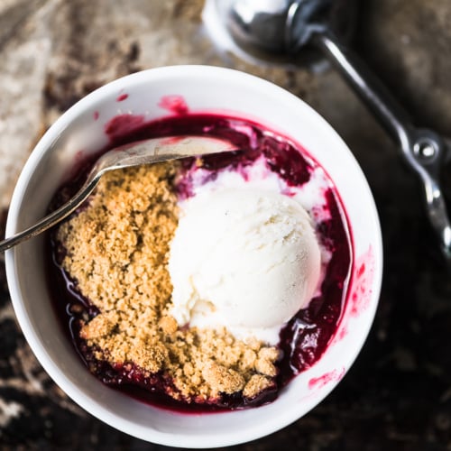 a small bowl of plum crumble with ice cream
