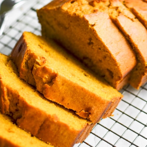 A pumpkin loaf cake, sliced, on a baking sheet.