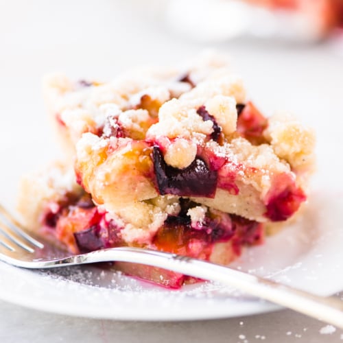 cardamom plum crumble on a white plate with fork