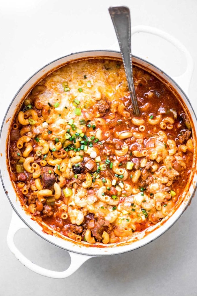 a large pot of chili mac and cheese with ladle