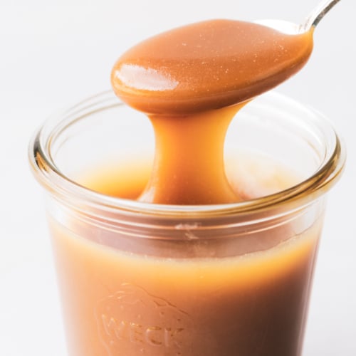 salted Maple Caramel Sauce in a jar with a spoon