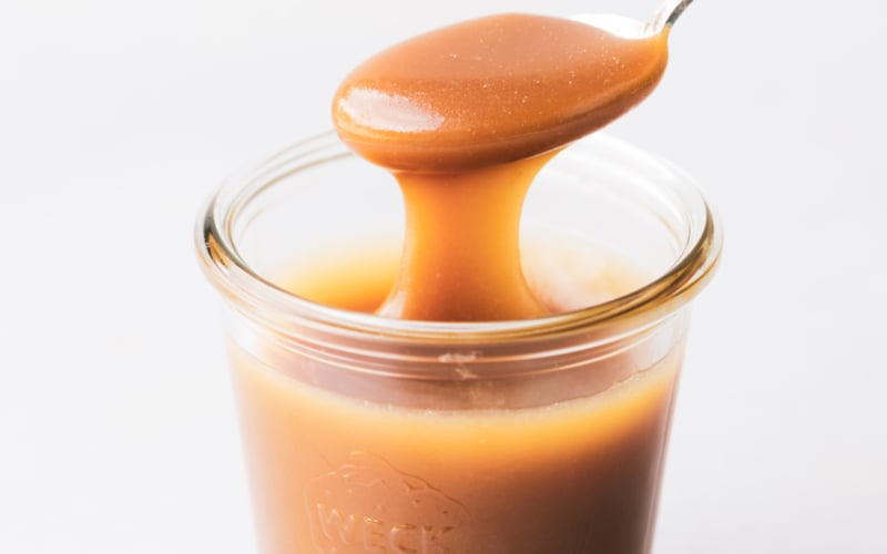 salted Maple Caramel Sauce in a jar with a spoon
