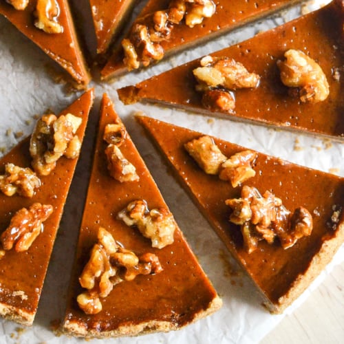 A pumpkin caramel tart with walnuts, sliced.