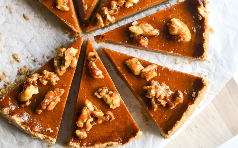 A pumpkin caramel tart with walnuts, sliced.