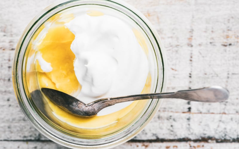 Fresh lemon pudding with whipped cream and a spoon