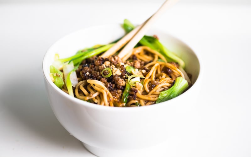 a bowl of dan dan noodles on a white table