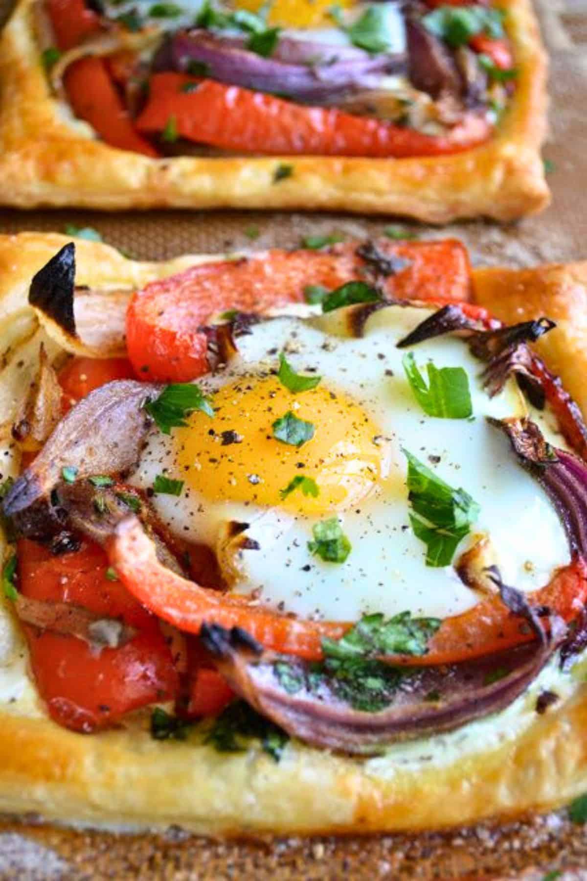 Red Pepper and Baked Egg Galettes from Jerusalem (the book) ~ these eggs baked in puff pastry are the ultimate breakfast in bed recipe! #eggs #breakfast #brunch #puffpastry #bakedeggs #breakfastinbed #mothersday #valentinesday #Christmasbreakfast #holidaybreakfast #ottolenghi #jerusalem Two puff pastry egg galettes ready to eat.