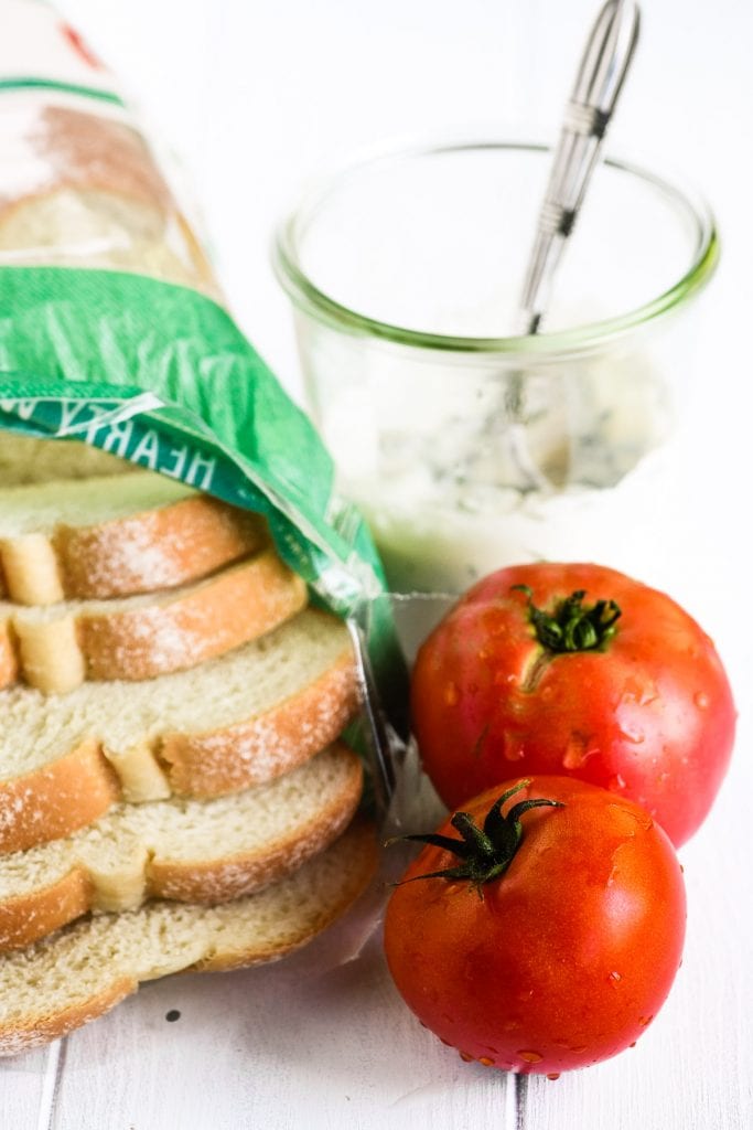 making tomato toast sandwiches with white bread, tomatoes, and basil mayonnaise