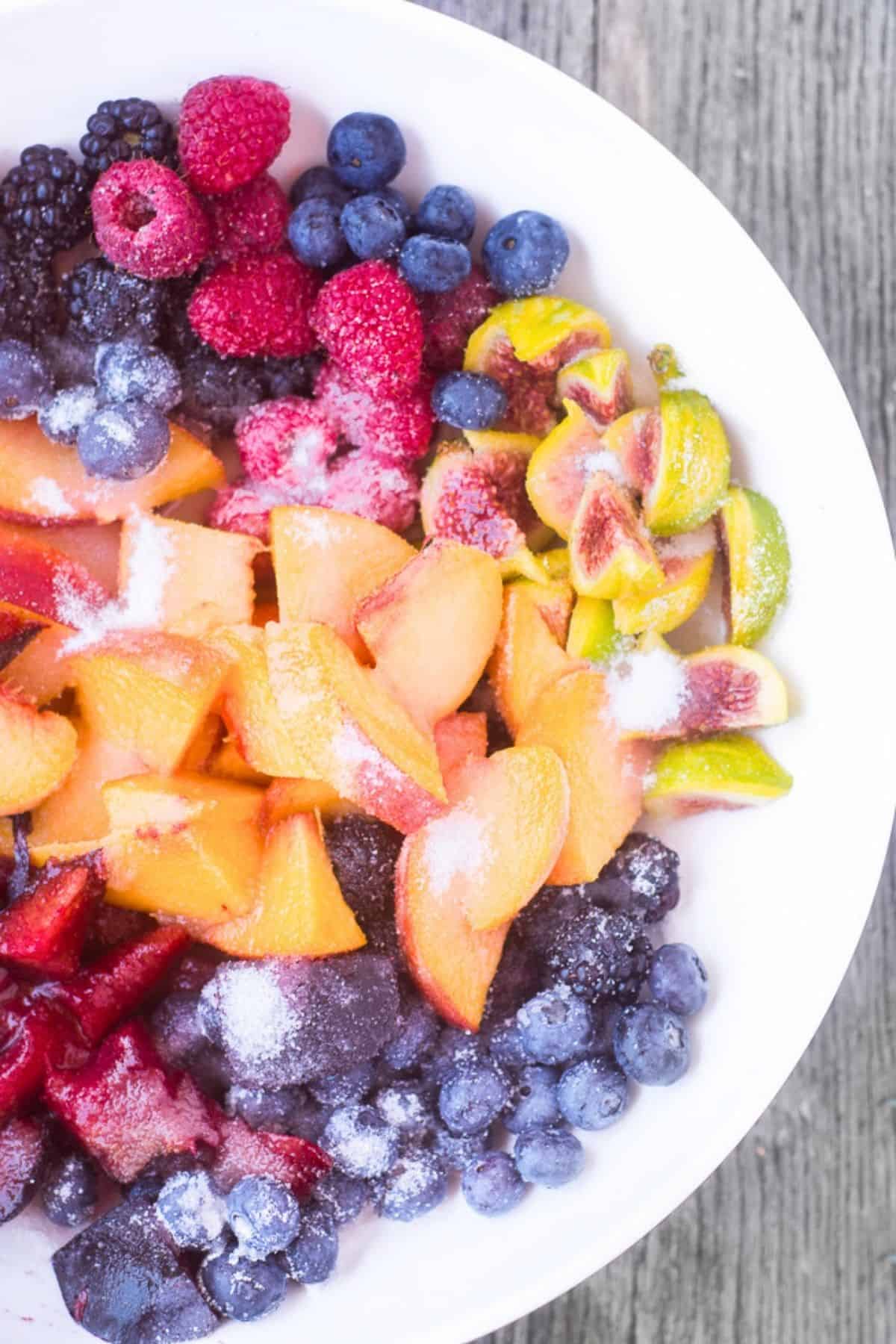 Mixed fruit in a bowl with sugar.