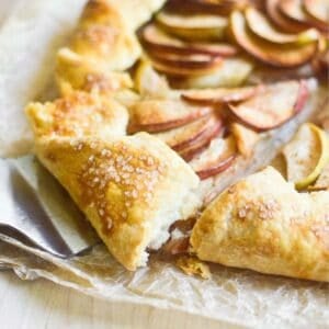 Slicing a rustic apple galette on parchment paper.